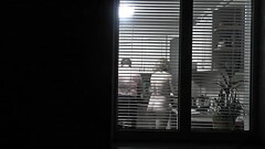 Peeping. Voyeur. Neighbor pervert voyeur in evening on street looks out window as naked sexy neighbor in kitchen prepares dinner for her husband. Naked in public. Naked at home. Family.  Outdoor Thumb